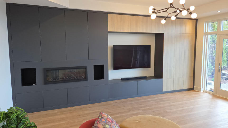 Mur de salon avec des panneaux gris et en bois clair, une télévision murale, un foyer encastré, un luminaire moderne au plafond, et un sol en bois clair.