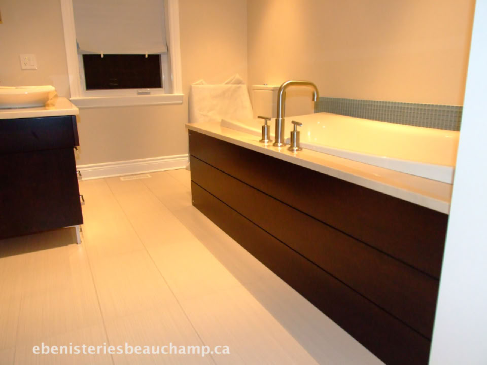 Salle de bain moderne avec un grand lavabo, un meuble en bois sombre, un miroir et un sol clair.
