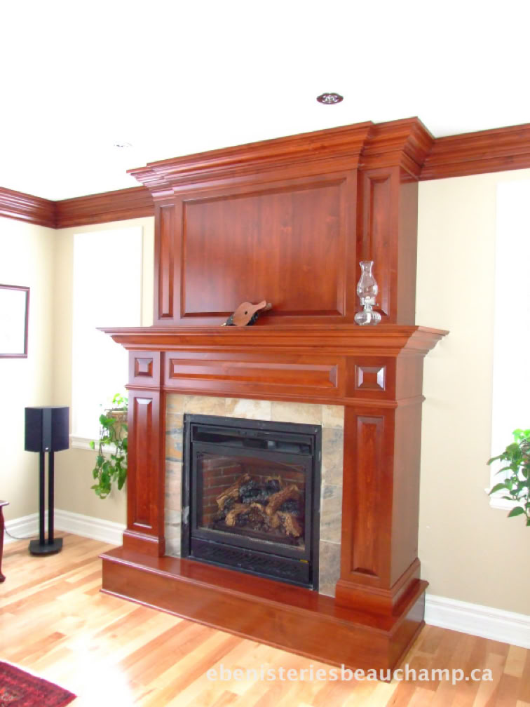 A wooden fireplace with decorative molding, a small sculpture, and a plant on the mantel, set against a light-colored wall with hardwood flooring.