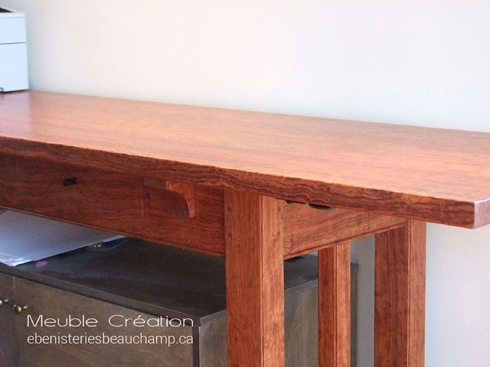 Table en bois avec des pieds en bois, posée contre un mur blanc.