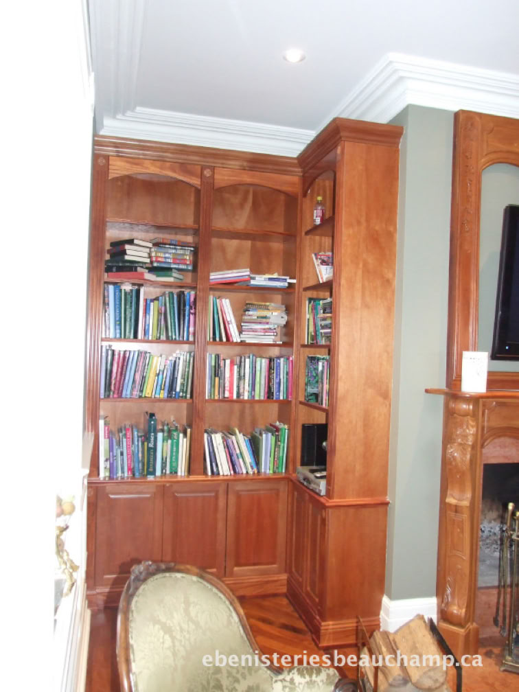 Wooden bookshelf filled with books in a corner of a room, next to a fireplace and a green armchair.