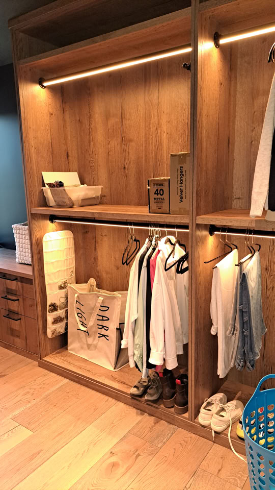 Armoire en bois avec étagères ouvertes, vêtements suspendus, chaussures en bas, et paniers de rangement.