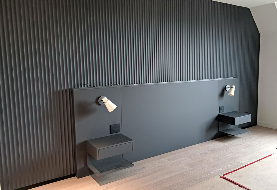 Mur intérieur gris avec deux appliques murales et deux petites étagères.