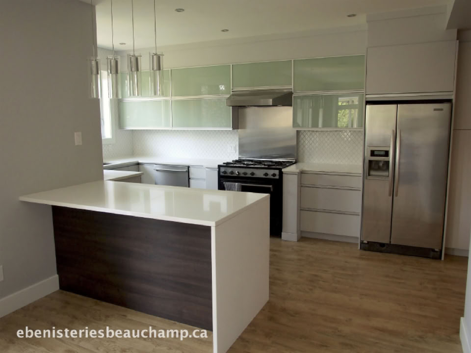 Cuisine moderne avec un îlot central, des armoires blanches, un réfrigérateur en acier inoxydable, un four et une cuisinière.