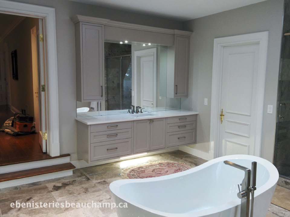 Salle de bain avec baignoire blanche, meuble-lavabo avec miroir, porte blanche et sol en carrelage.