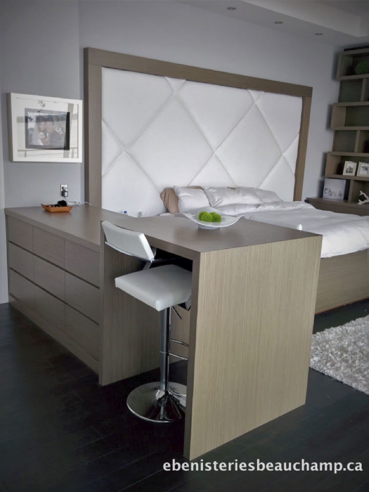 Modern bedroom with a large bed featuring a white tufted headboard, a wooden dresser, a high chair, and a small table with a bowl on it.