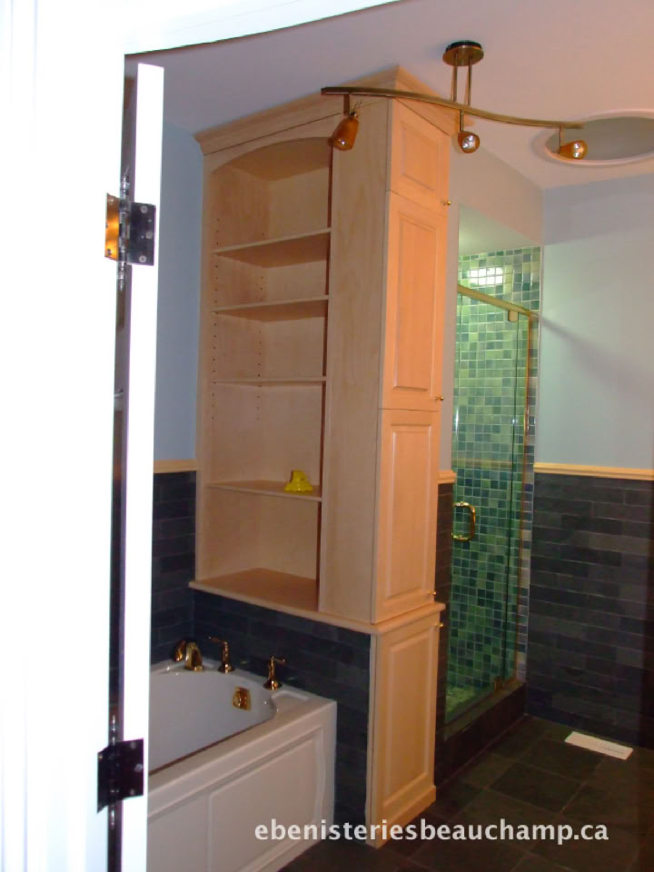 Salle de bain avec une baignoire blanche, une étagère en bois, et une douche avec des carreaux verts.