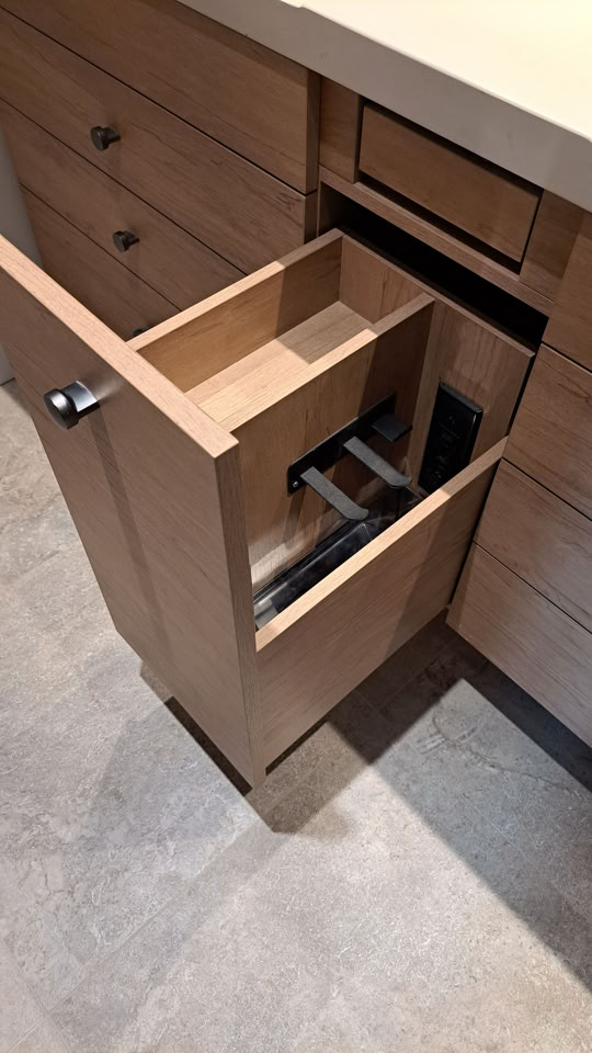 Tiroir de salle de bain en bois ouvert avec un compartiment pour poubelle intégré.