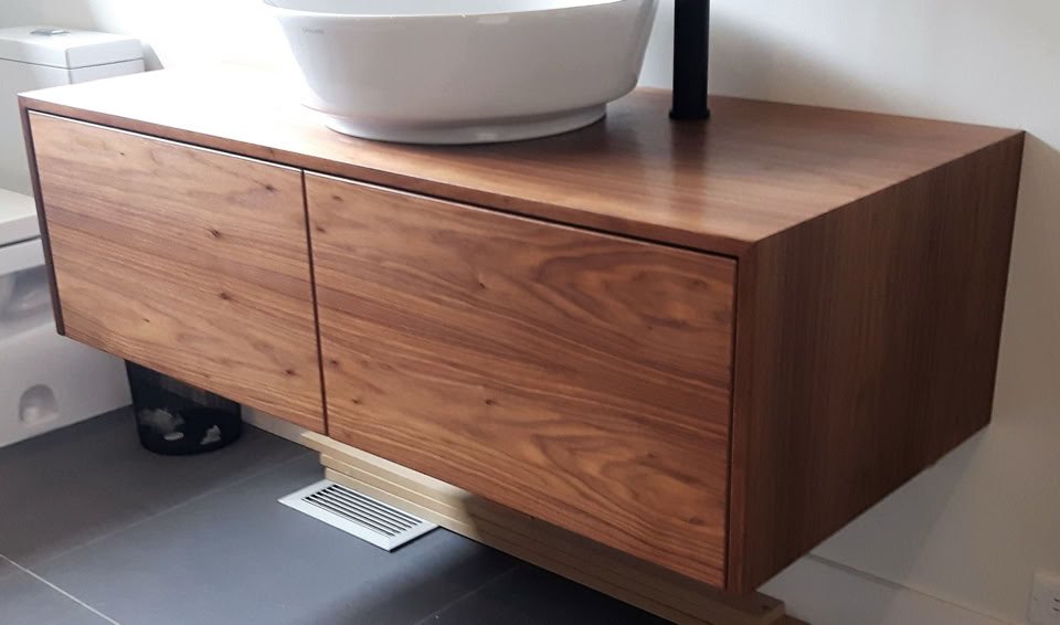 Meuble de salle de bain en bois avec un lavabo blanc posé dessus.